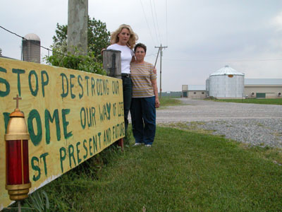 Pam Broering, left, and Lucille Monnin stand in Monnin's front yard on Ross-Medford Road two miles west of North Star this morning, with a sign protesting the proposed expansion of Ross-Medford Farm LLC. The farm has applied for permits from the Ohio Department of Agriculture to expand its operation to 1.27 million laying hens, add four chicken barns, a manure storage building and a 2 million gallon egg wash storage pond. Broering lives about 1,600 feet away from where the storage pond would be constructed.<br>dailystandard.com