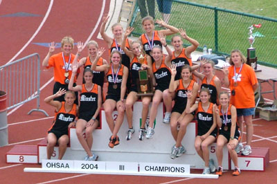 The Minster girls track team members raise four fingers to signify winning a fourth straight Division III girls state track title on Saturday at Jesse Owens Memorial Stadium on the campus of The Ohio State University. The Wildcats now have 12 state team titles in 30 years in girls track. Stories and pictures from the state meet for all area teams can be found starting of page 1B.<br>dailystandard.com