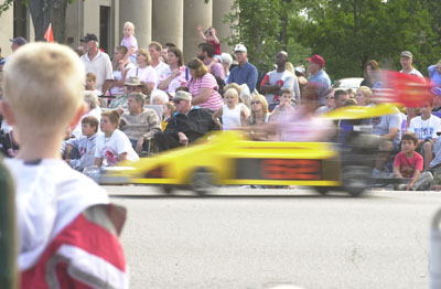 One of the small motorized cars, driven in fast-changing precision formations during the Lake Festival parade by members of a Masonic organization, speeds past crowds of onlookers Saturday.<br>dailystandard.com