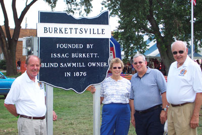 Stopping by a commemorative marker at the west edge of Burkettsville are, left, Paul Burkett of Columbia City, Ind., Karen Burkett Lowe of Columbus, Ind., Gale Burkett of Worthington, and Kent Burkett of Clayton. The great-great-grandchildren of Isaac Burkett, a blind sawmill operator who founded the town in 1876, came Sunday to attend Burkettsville's second community picnic. <br>dailystandard.com