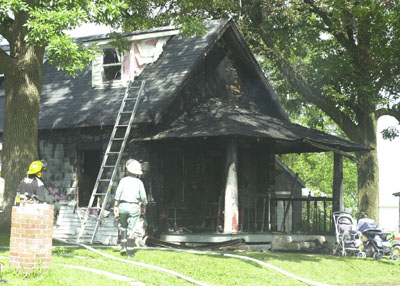 Firefighters stand before the charred home of Daniel Ganger, 403 N. West St., Rockford. The family, which includes seven children ranging from 15 months to 15 years, lost everything in the Tuesday morning blaze. They suspect a child playing with a lighter may have caused the fire.<br>dailystandard.com