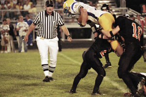 A Marion Local ballcarrier gets hit hard by Minster's Alex Stricker and a teammate during their game on Friday night.<br>dailystandard.com