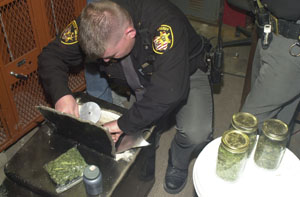 Mercer County Sheriff's Deputy Doug Timmerman pulls evidence out of a confiscated safe in the evidence room at the sheriff's office Wednesday afternoon.<br>dailystandard.com