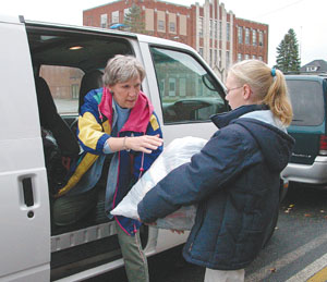 Immaculate Conception School Principal Kathy Mescher reaches for a bag of donated clothes from student Zoe Kriegel while packing a van last week. Kriegel was one of four students who traveled to Kentucky last weekend.<br>dailystandard.com