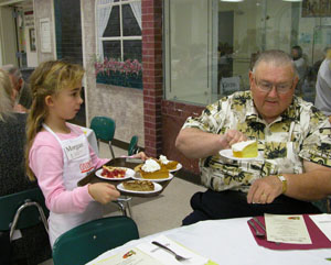 Eight-year-old Morgan Beatty shows diner Don Hare of Celina the large variety of tempting desserts prepared by Giving Thanks workers. Beatty was one of several dozen servers on hand at Celina High School.<br>dailystandard.com