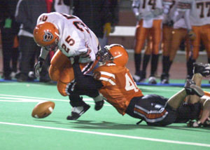 Coldwater's Ross Homan, 25, gets stripped of the ball by Versailles' Alex Davis during Friday's Division IV state semifinal at Dayton's Welcome Stadium. Versailles' defense and running game on offense prevailed in a 14-0 Tigers win.<br>dailystandard.com