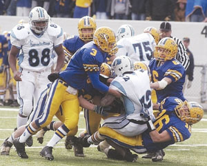 St. Marys' Corey Vossler, 3, Mark Riesen, 6, and Nick Yahl, 16, drag down a Cleveland Benedictine ballcarrier during their Division III state final game on Saturday. Benedictine defeated St. Marys, 27-14.<br>dailystandard.com