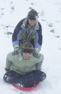 Maria Huber and Emily Freytag, top, sled down a hill behind the Dannon Company in Minster on Wednesday afternoon.<br>dailystandard.com