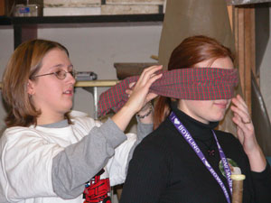 Parkway High School student Ashleigh Garrison ties a scarf around classmate Kristin Nuttle's eyes before she attempts to squash a pinata with a baseball bat.<br>dailystandard.com