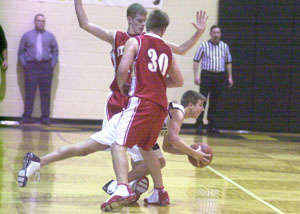 Parkway's Jordan Heckler, with ball, is trapped by the St. Henry tandem of Andy Puthoff, 30, and Nate Stahl, back, during their Midwest Athletic Conference makeup game on Tuesday. St. Henry defeated Parkway, 60-38.<br>dailystandard.com