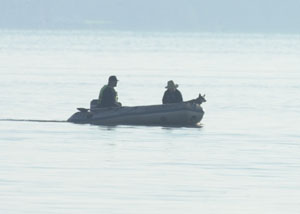 A search boat with a canine unit aboard crisscrosses an area between the boat launch ramp and the spillway Sunday morning. Other boats were kept out of the area during the search because fumes from motors interfere with the dog's scening ability.<br>dailystandard.com