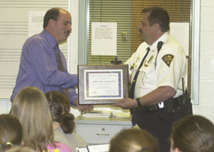 Celina High School band director Chuck Sellars accepts a plaque from Celina Police Chief Dave Slusser during ceremonies held Wednesday morning in the band room.<br>dailystandard.com