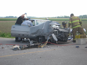 Celina firefighters work feverishly to free driver Jordan Steen, 16, 12175 state Route 707, Mendon, following a Wednesday crash on state Route 29 west of Celina, as Mercer County Sheriff's Deputy Matt Grunden holds a bag of IV fluid. The youth, who just completed his sophomore year at Parkway High School, was pronounced dead on arrival at an area hospital becoming Mercer County's first 2005 traffic fatality.<br>dailystandard.com