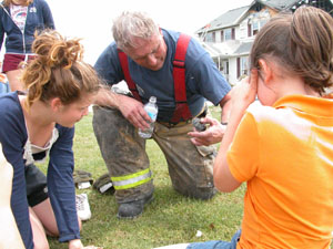 Lt. Bob Schulte of the Celina Fire Department examines a pet turtle he found inside a rural Celina house that sustained extensive fire damage Wednesday morning. Family members, Morgan Miesse, 10, at right, and Marie Miesse, 12, at left, are surprised to see 