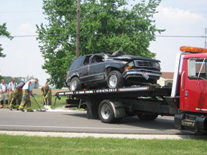 Coldwater firefighters sweep up debris Wednesday afternoon as wrecker personnel prepare to transport a heavily damaged Ford Explorer from the scene of a fatal accident along state Route 118 north of Coldwater. John J. Ford, 42, 117 First Ave., Coldwater, the driver and sole occupant, was pronounced dead at the scene.<br>dailystandard.com