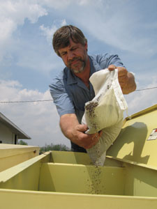 Shelby County farmer Chris Gibbs pours native prairie grass and wildflower seeds into a planter last May to plant in his fields, which will become habitat for wildlife.<br>dailystandard.com