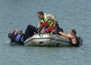 Celina Fire Chief Doug Kuhn slips into the water with the help of Celina Assistant Police Chief Calvin Freeman as Celina firefighter Steve Hemmelgarn takes a break from diving in the pond at Eastview Park.<br>dailystandard.com