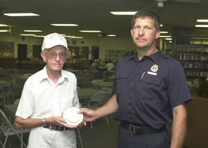 Celina firefighter/paramedic Mike Bruns gives a free smoke detector to Ed Jeffries Sr. at the Mercer County Council on Aging. Fellow firefighters will be going door to door in coming weeks to make sure each home in their coverage area has a working detector.<br>dailystandard.com