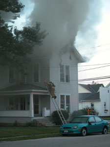 A Celina firefighter climbs a ladder as smoke rolls out of an attic on West Anthony Street in Celina early this morning. The home, a rental property, was occupied by tenants living on both floors of the two-story structure. Thanks to a quick-thinking motorist, seven adults and a dog escaped the burning house without injury. The name of the homeowner was not available at press time.<br>dailystandard.com