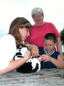 Theo Schlater, 10, of Minster, clips the toenail of one of the rabbits he is showing next week at the Auglaize County Fair in Wapakoneta. Schlater gets a little help from his mother, Lori, holding the rabbit, and grandmother, Barb Osterloh. All three generations are active in the Stitch 'N Snack 4-H Club in Minster.<br>dailystandard.com