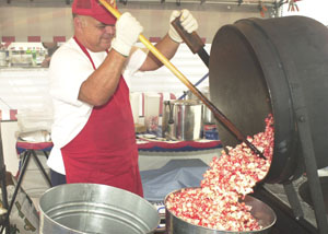 Concessionaire Dan Mango of St. Petersburg, Fla., finishes a batch of flavored kettle corn at the Mercer County Fair. The tent at the foot of the midway also includes jewelry creations by his wife Joann, who inscribes tiny grains of rice.<br>dailystandard.com