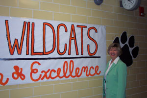 Gayl Ray stands by a Minster Wildcat banner touting tradition and excellence. Ray, an Akron native, assumed the duties of Minster Local Schools superintendent Aug. 1. She replaces Hal Belcher who retired after 22 years at the helm.<br>dailystandard.com