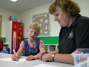 Preschool teacher Pam Cupp helps student Bethanie Christman print her name during class recently at Stepping Ahead Learning Center in Coldwater. Although many schools in metropolitan areas require youngsters to be academically skilled in order to be eligible for preschool, local teachers concentrate more on social behavior. <br>dailystandard.com