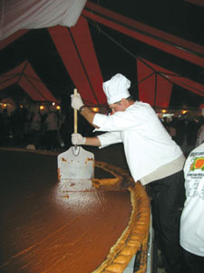 Jess Siegel, a member of the New Bremen Giant Pumpkin Growers, uses a large paddle to cut what is believed to be the world's largest pumpkin pie. The pie, baked and served Saturday at Crown Pavilion in New Bremen, measured 12 feet 4 inches and weighed 2,020 pounds. Below, Tyler Wolfe of St. Marys stands beside the recipe for pumpkin pie as he savors a slice of history. Visitors purchased servings for $1 each, with the money going to defray costs associated with the ambitious project.<br></br>dailystandard.com