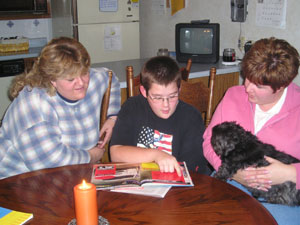 Fifth-grader Austin Selzer of Celina reads to his aunt, Shelly Figel, left, and his mom, Missy Stelzer, after a medical device was attached to his ear to halt the severe stuttering problem, which he has had since he was 6 years old. <br></br>dailystandard.com