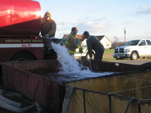 Area firefighters dump water into portable tanks Tuesday afternoon as three departments battle a blaze at the home of Steven and Dayle Ross, 5847 state Route 118, Coldwater.<br></br>dailystandard.com