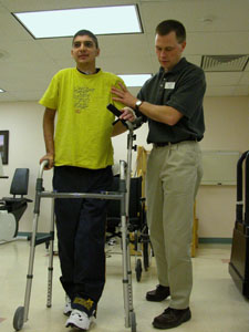 Jeromie McNeilan of Montezuma gets a helping hand from physical therapist Matt Dwenger while learning to walk again at Joint Township District Memorial Hospital, St. Marys. McNeilan, 20, was injured critically in a traffic accident in October on state Route 274 near the Shelby-Auglaize County line.<br></br>dailystandard.com