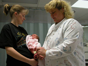   Tina Brunswick of Coldwater holds her third child, Emily, as Registered Nurse Anne Opperman takes a look at the infant's Hugs security bracelet. The bracelets are part of a software security program that tracks the location of each newborn at Mercer County Community Hospital, Coldwater.<br></br>dailystandard.com