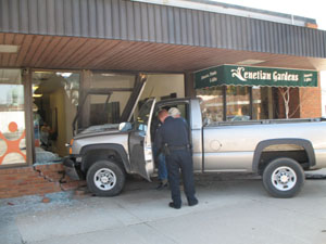 Celina Patrolman John Barker talks with driver Robert Holscher after the Yorkshire man's pickup truck plowed into a storefront on West Market Street in Celina on Monday.<br></br>dailystandard.com