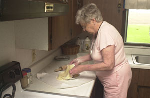 Helen Klosterman, 89, sits and crochets an afghan in her Montezuma home and places dough in a pan for a pie. At an age when many people are slowing down, Klosterman continues to bake, sew and crochet for her family. The display of afghans at left is just a sample of her handiwork. She has made at least one for each of her five children, 17 grandchildren and 38 great-grandchildren.<br></br>dailystandard.com