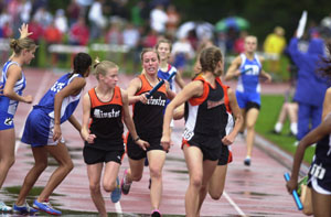 Minster's Katie Dahlinghaus, center, passes the baton to teammate Bernadette Burke, left, during the 3,200-meter relay on Friday at the state track meet in Columbus. Versailles' Rene Eilerman, right, is also looking back in the picture awaiting the baton from an unidentified teammate. Minster finished third with Versailles a distant sixth.<br></br>dailystandard.com