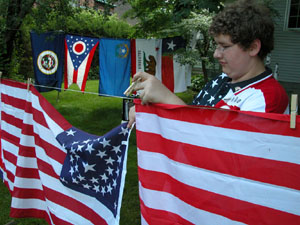 Evin Bachelor hangs one of his flags on the clothesline behind his Main Street home in Celina on Wednesday, the observance of Flag Day. Bachelor, 13, began a flag collection after Sept. 11 and hopes to continue the hobby into adulthood.<br></br>dailystandard.com