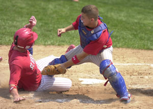 St. Henry's Kyle Bruggeman, left, is called safe sliding into home plate as Crestview's Josh Harmon applies the tag during the ACME district tournament at Minster on Sunday. The four Grand Lake area teams still remaining started the tourney 1-0 as St. Henry, Coldwater, Minster and St. Marys all posted impressive victories over teams from Van Wert and Shelby County teams.<br></br>dailystandard.com