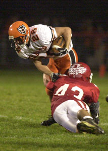 St. Henry's Christopher Reichert, front, put a hit on Coldwater running back Tony Harlamert, top, during their Midwest Athletic Conference contest on Friday night at the Wally Post Athletic Complex. <br></br>dailystandard.com