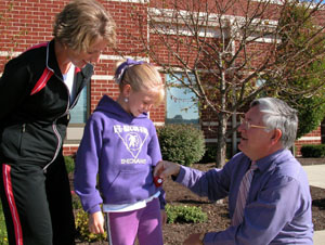 Michaela Fullenkamp, a fourth-grader at Fort Recovery Middle School, receives a pedometer from school Principal Ted Shuttleworth so she can take part in a new wellness program implemented Monday. At left is Amy Wendel, a member of the school's wellness committee who is spearheading the Live It program.<br></br>dailystandard.com