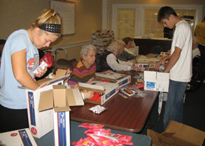 Marion Local High School freshmen Rachel Puthoff and Andrew Kremer help residents of The Gardens at St. Henry pack boxes of food and personal care products bound for area military personnel overseas. St. Henry students are collecting items this week in conjunction with the same project.<br></br>dailystandard.com