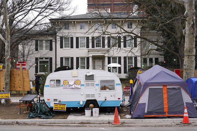 A camper and tent are shown outside the University of Michigan's Presidents House on campus in Ann Arbor, Mich., Thursday, Jan. 20, 2022. A financial payout for more than 1,000 people — mostly men — who say they were sexually assaulted by former University of Michigan sports doctor Robert Anderson is the latest multimillion-dollar settlement involving schools faced with sexual misconduct scandals. (AP Photo/Paul Sancya)