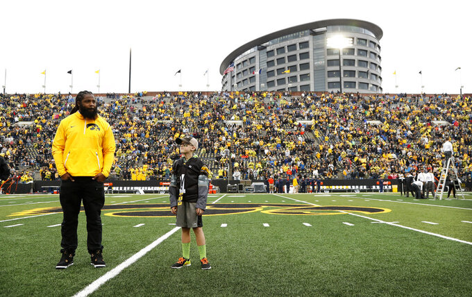 FILE - Atlanta Falcons defensive end and former University of Iowa player Adrian Clayborn, left, and Kid Captain Maddox Smith are honored on the field before an NCAA college football game between Iowa and Illinois in Iowa City, Iowa, Oct. 7, 2017. "The Wave" at Iowa home games, where fans salute children from the nearby hospital battling cancer and their families, has become college football's neatest new tradition. The University of Iowa announced that patients at UI Stead Family Children's Hospital will get to pick the songs that accompany the Hawkeye Wave, at which fans attending games at Iowa's Kinnick Stadium wave to patients at the adjacent hospital. Now at every Iowa home game this year, the hospital's Kid Captain — a Children's Hospital patient who is is picked to be honored at each Iowa football game — will help select a new song to accompany the Hawkeye Wave. (AP Photo/Charlie Neibergall, File)