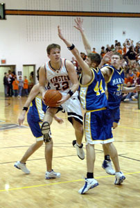 Minster's Dane Sommer, with ball, looks for a teammate to pass to in the middle of a trio of Marion Local defenders. Sommer scored a game-high 19 points in the Wildcats' 59-37 victory.<br>dailystandard.com
