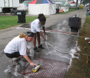 Scrubbing mats at Donna's Midway Diner keeps Chicago resident Aimee Wilson, in the foreground, and Detroit resident Kim Brown busy Monday afternoon at the Mercer County Fairgrounds. The 154th Banner Fair officially opens with a 3 p.m. ceremony today.<br></br>dailystandard.com