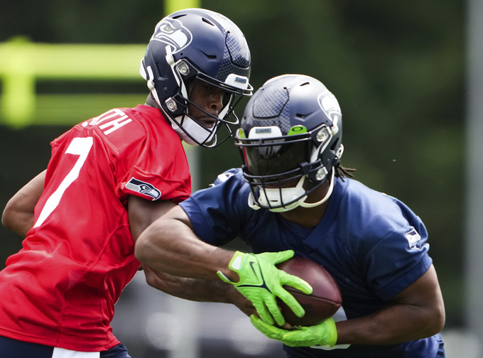Seattle Seahawks quarterback Geno Smith (7) hands off to running back Kenneth Walker III, Monday, May 22, 2023, at the team's NFL football training facility in Renton, Wash. (AP Photo/Lindsey Wasson)