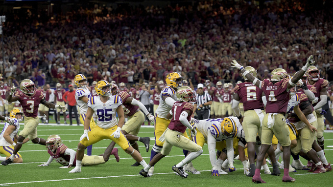 FILE - The extra point kick by LSU place kicker Damian Ramos (34), fourth left, is blocked by Florida State defensive back Shyheim Brown (38), on ground below Ramos, leading Florida State to a 24-23 victory in an NCAA college football game on Saturday, Sept. 4, 2022, in New Orleans. The two teams will face each other again on Sept. 3, 2023, in Orlando, Florida, in a game that will be aired on ABC. (AP Photo/Matthew Hinton, File)